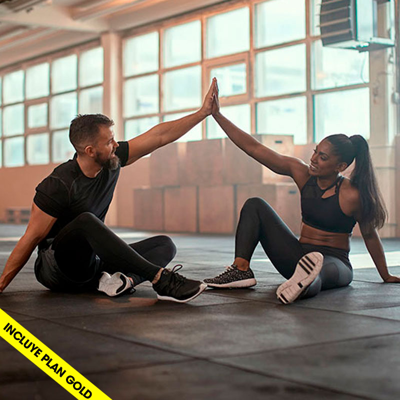 hombre y mujer sentados en el suelo de una sala de un gimnasio al final de un entrenamiento